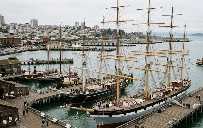 Historic wooden sailing ships docked at the waterfront of a renowned maritime museum.